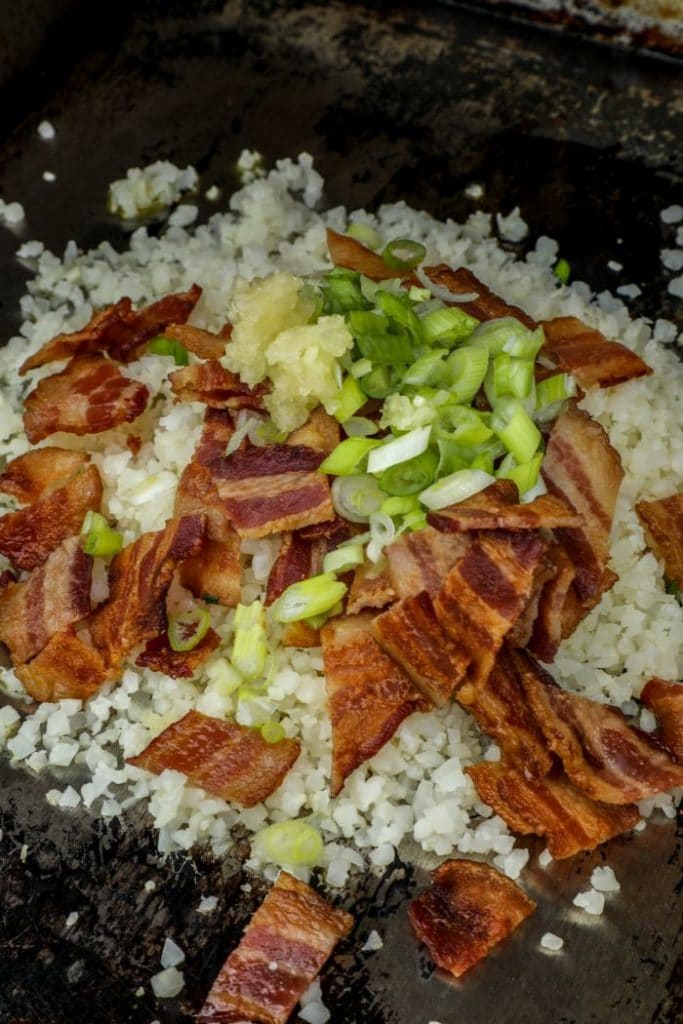 Partially cooked Bacon Cauliflower Fried Ric on a griddle pan