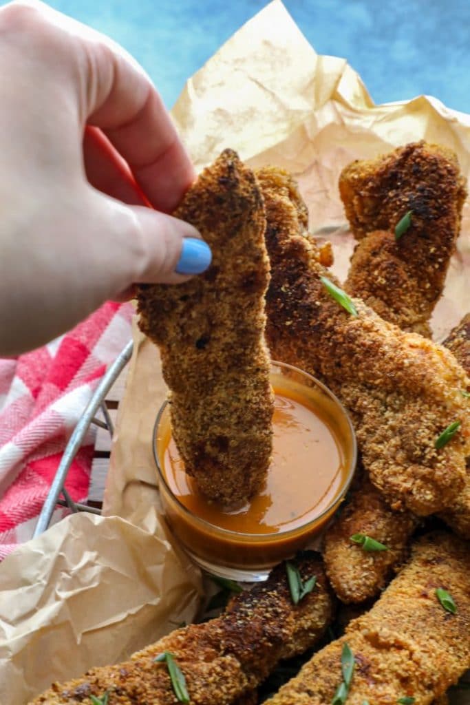 Dipping the cajun almond flour chicken tender into keto BBQ mustard sauce