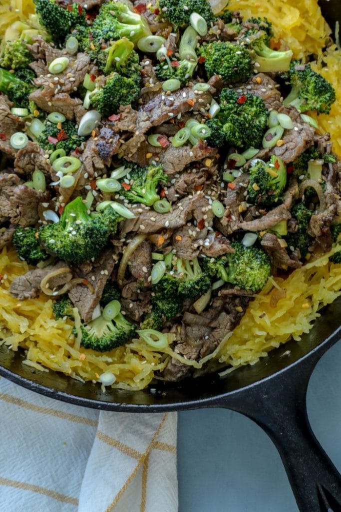 A cast iron pan with beef and broccoli with spaghetti squash
