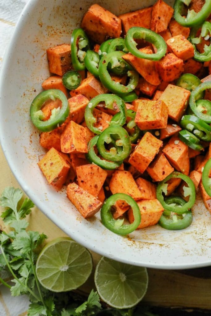 Spicy and Smoky Cumin Roasted Sweet Potato ingredients in a bowl and tossed with spices and oil. 