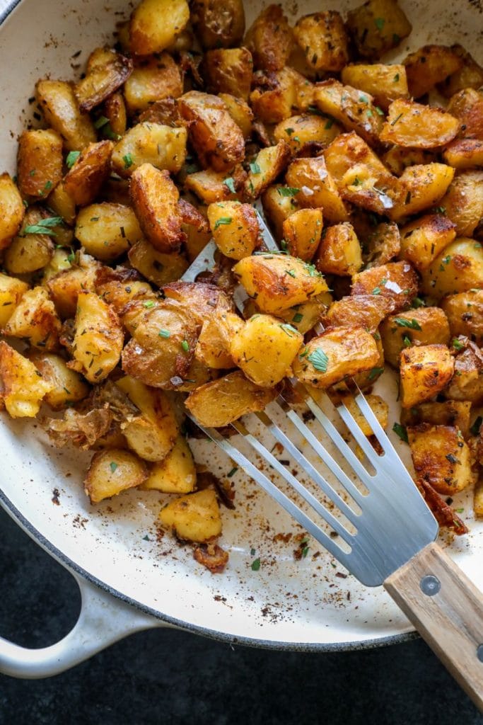 Crispy Garlic Herb Roasted Potatoes with a spatula