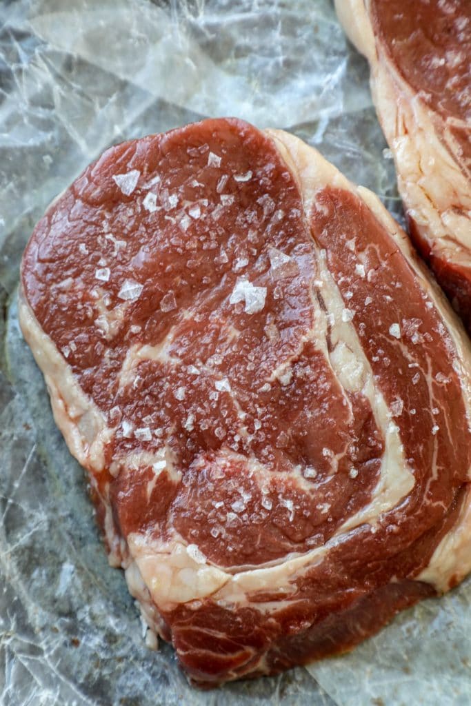 Angus beef steak being dry brined with salt 