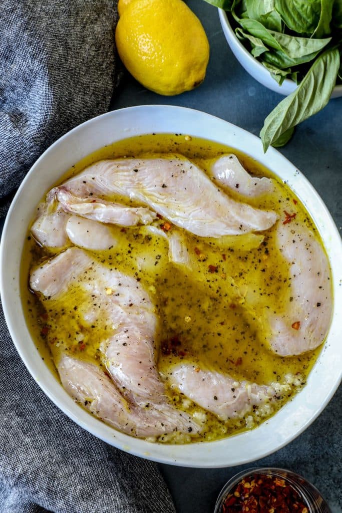 Raw chicken marinating in lemon juice mixture