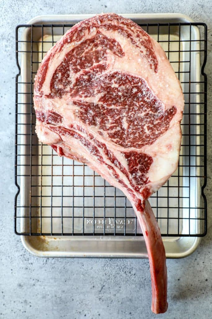 A raw wagyu tomahawk on a baking sheet to be seasoned