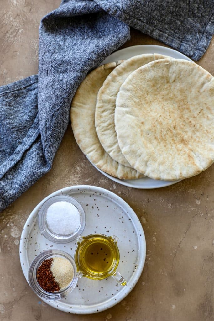 Whole pita breads and seasonings on a board 