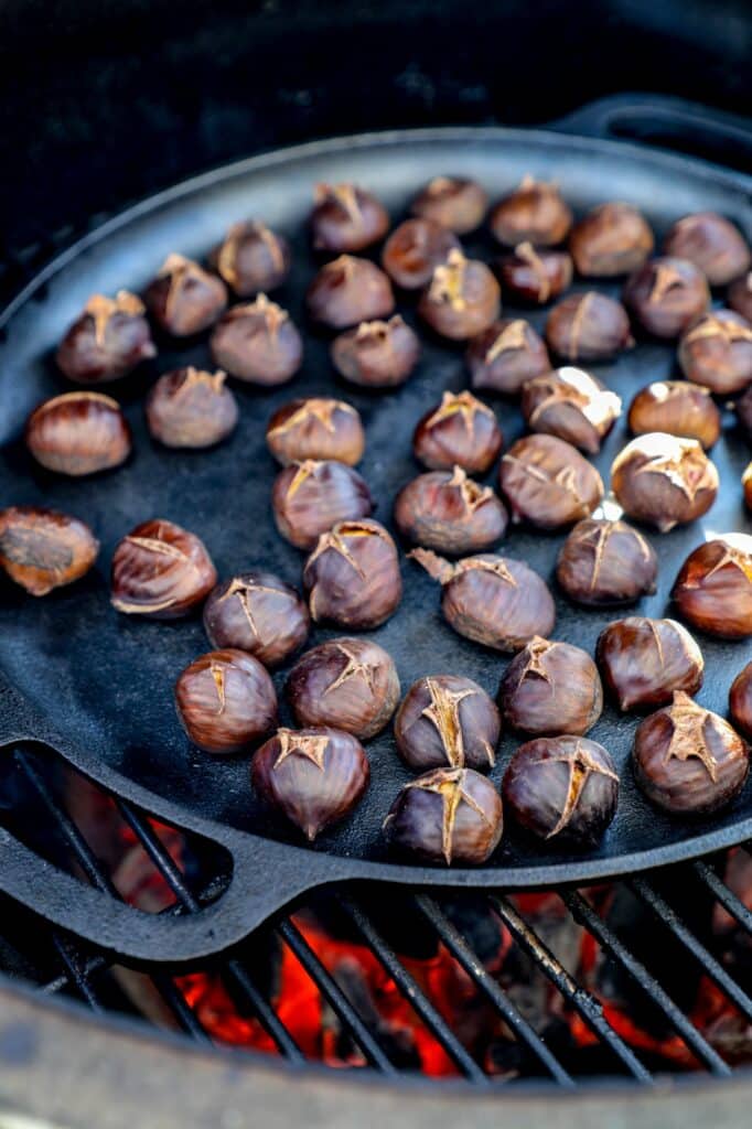 Chestnuts in a cast iron pan over a fire on the grill. 