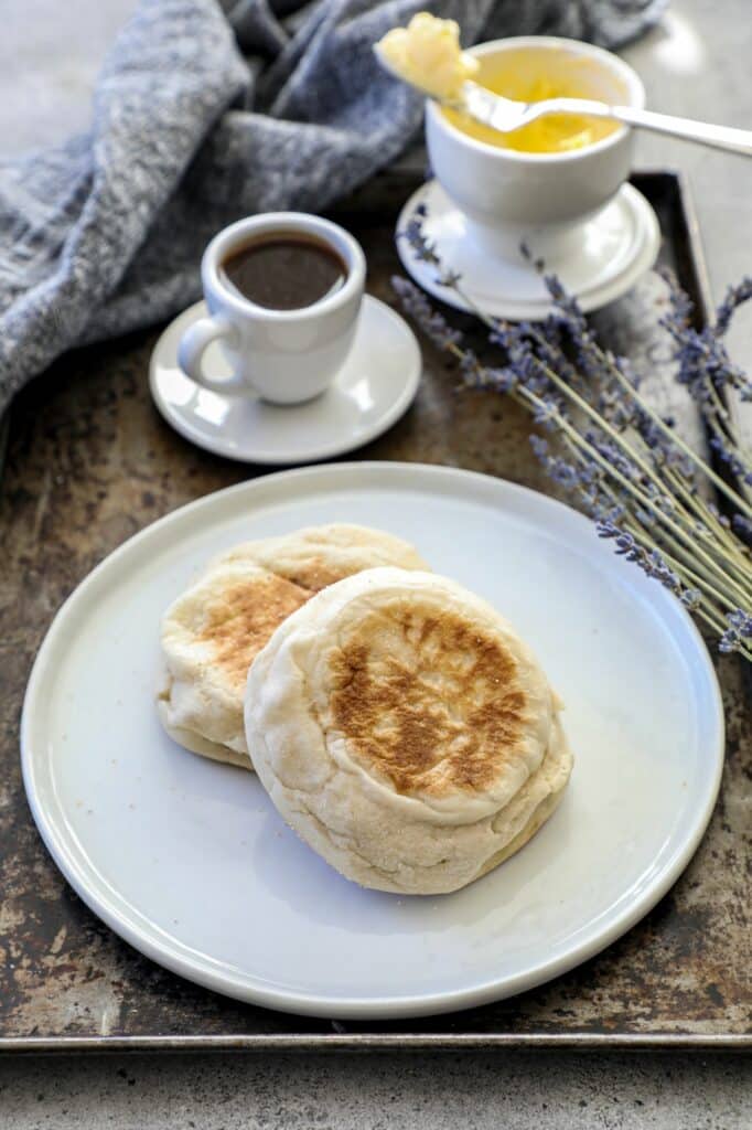 Whole English muffin sitting on a white plate 