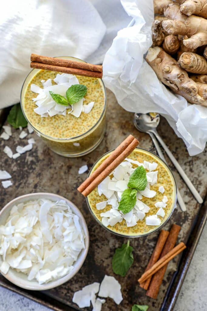 Top view of golden milk chia pudding jars with cinnamon sticks on top. 