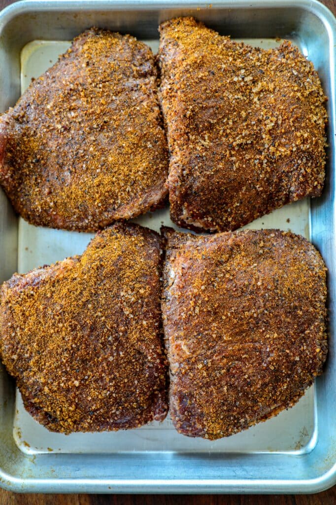 Prepped beef cheeks in dry rub for the smoker