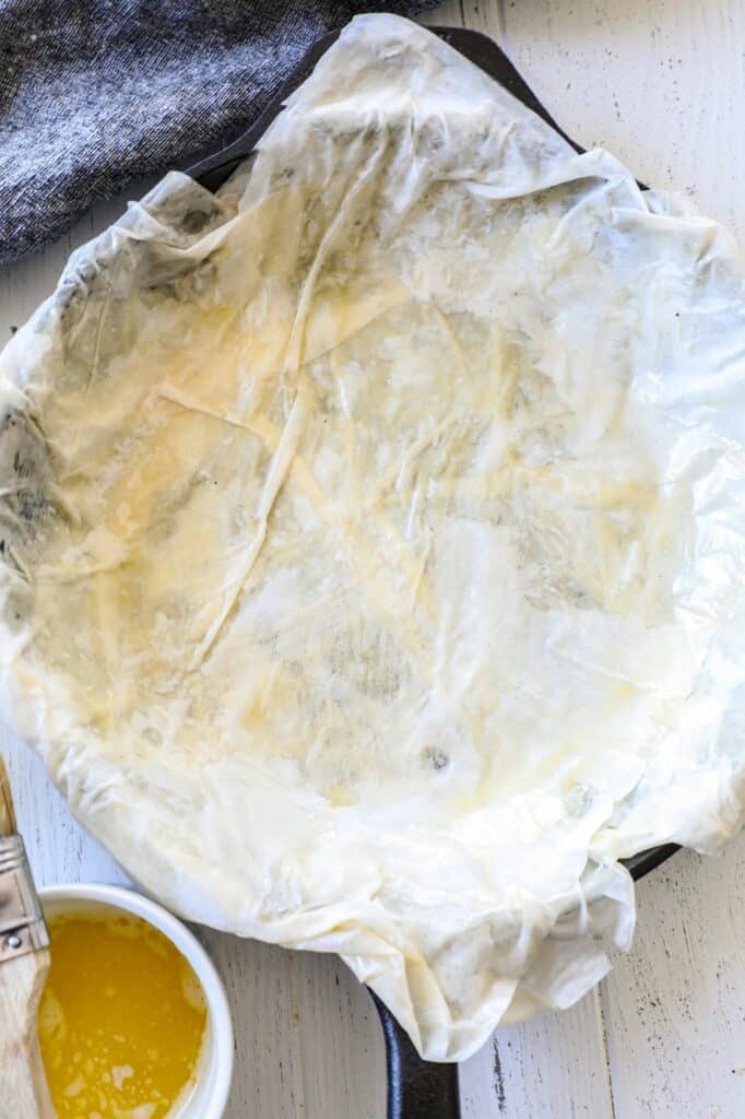 The first few layers of building a phyllo dough tart in a cast iron skillet 