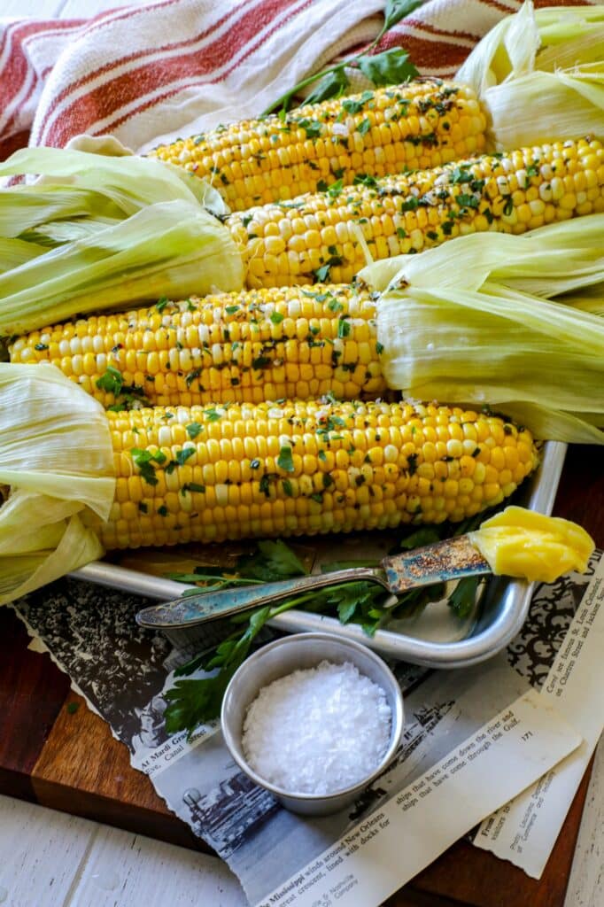 Smoked corn on the cob on a baking sheet with butter and salt on the side. 