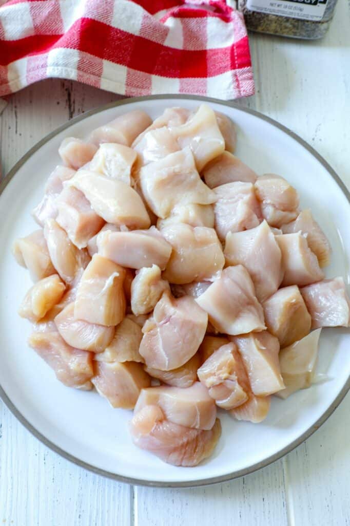 Chicken breast diced into cubes on a white plate. 