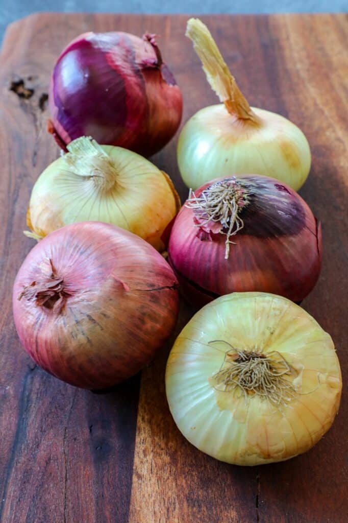 Red and yellow onions on a wooden cutting board. 