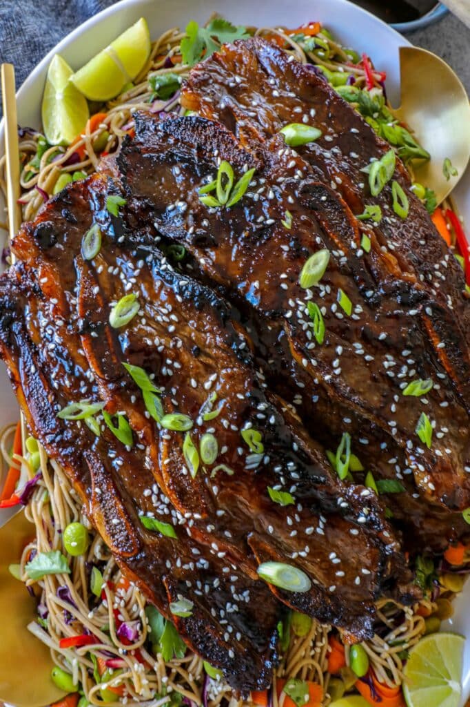 Beef Flanken Ribs on a bed of noodles on a serving platter. 