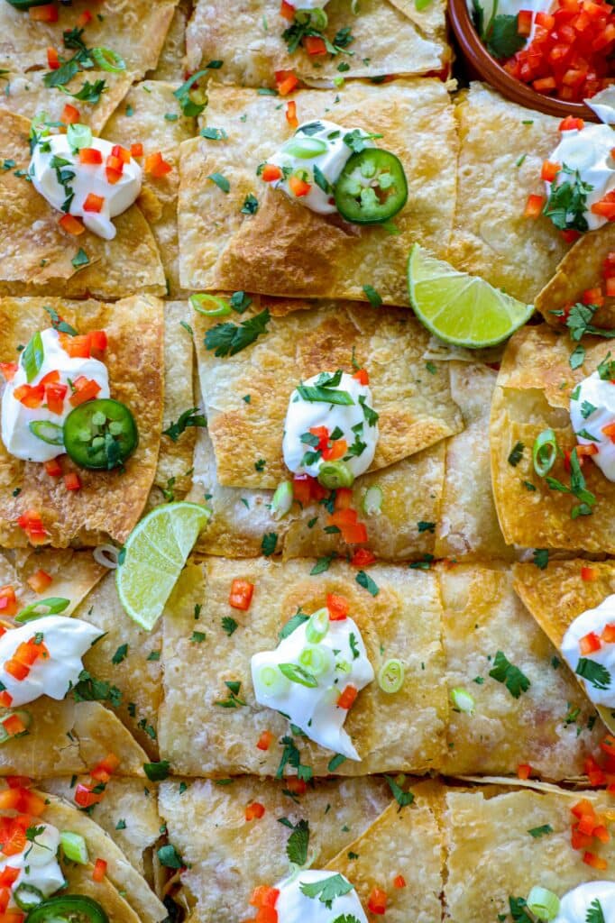 Overhead shot of Sheet pan Crunchwrap Supreme cut into pieces with toppings. 