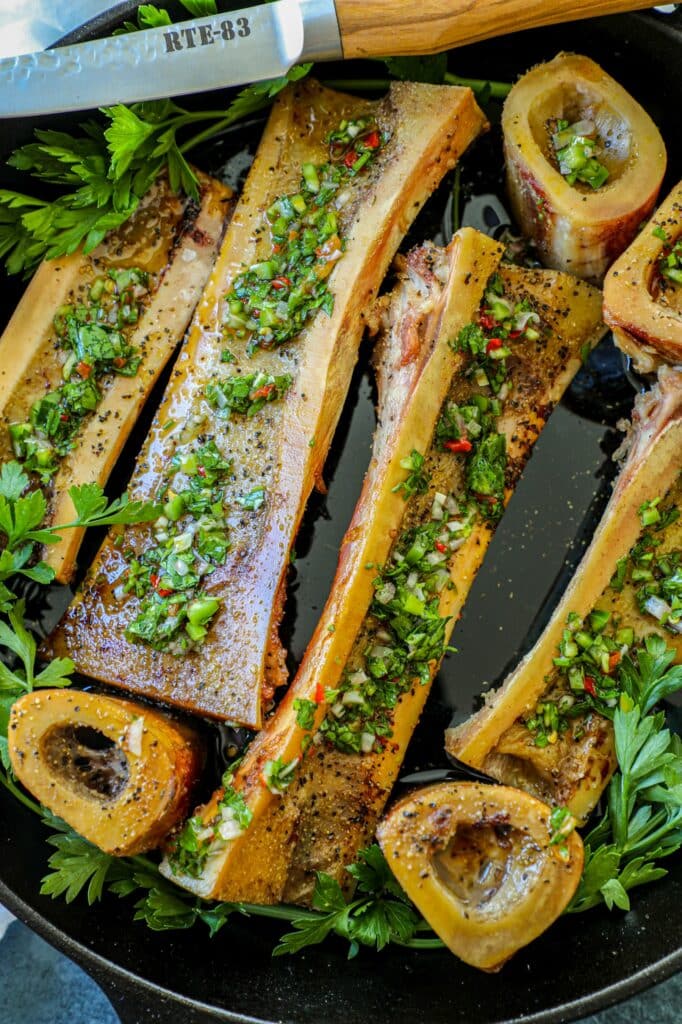 Smoked Bone Marrow bones in a cast iron pan topped with chimichurri. 