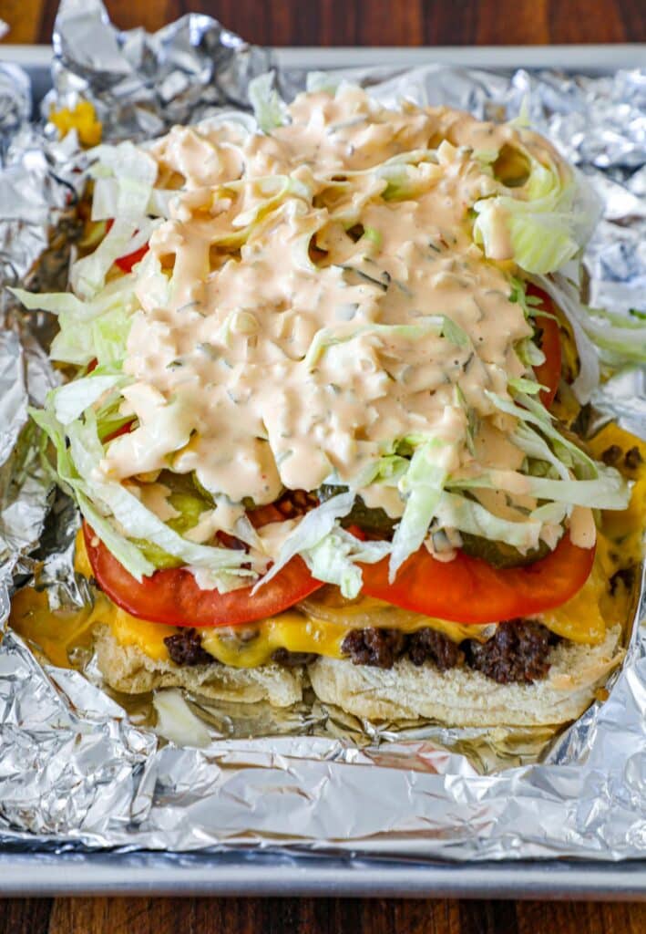 adding the toppings to the animal style burgers
