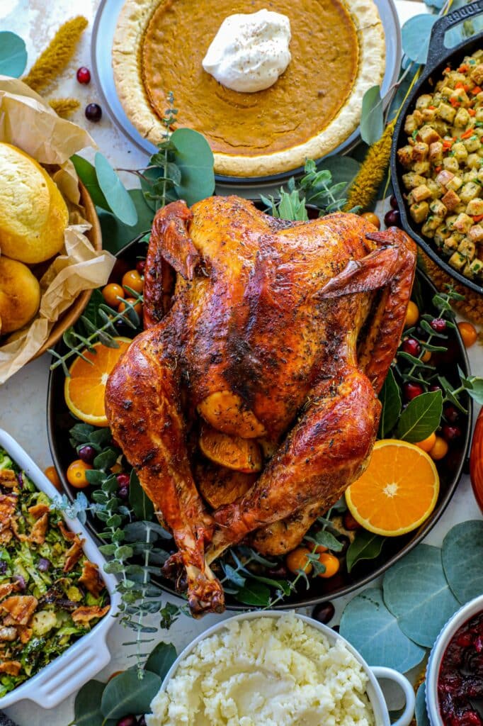 Cheesecloth Herb Butter Turkey on a serving platter with Thanksgiving sides around it. 