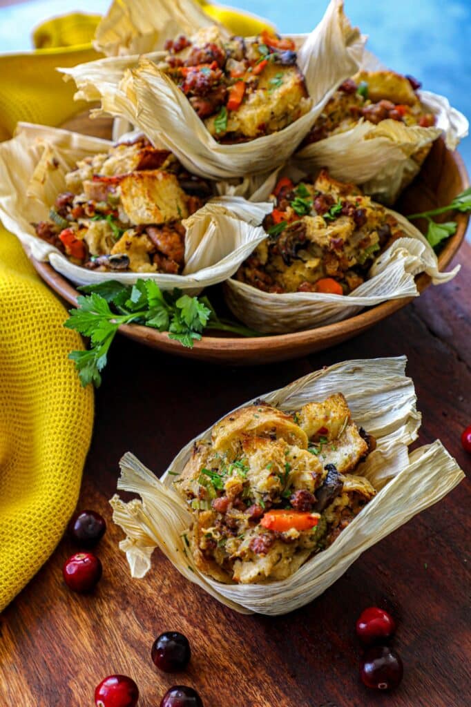 Sausage Stuffing Muffins stacked on top of each other in a bowl with one muffin in front of the bowl. 