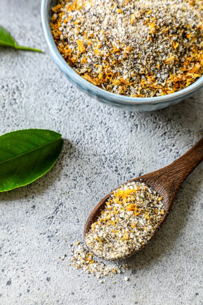 Lemon Pepper Seasoning in bowl with a wooden spoon next to the bowl full of seasoning. 