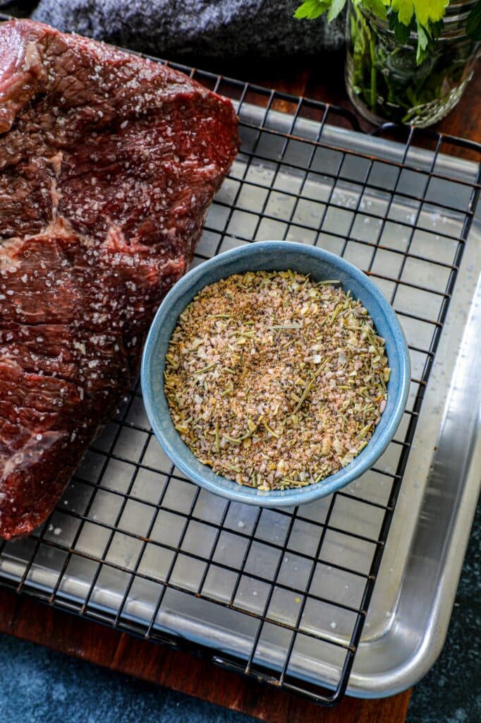 Prime Rib Rub in a small bowl next to a round roast. 