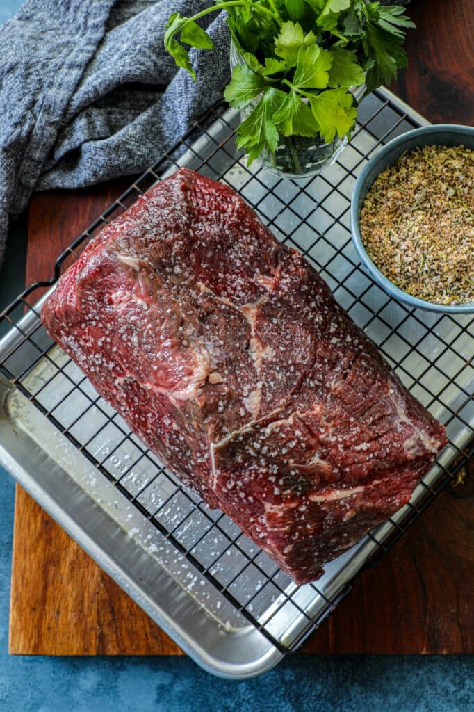 Bottom round roast seasoned with salt on a wire rack.